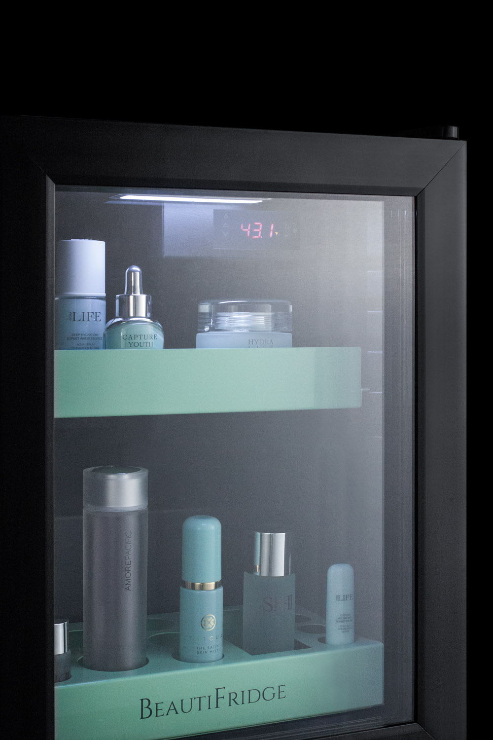 BeautiFridge compact cosmetics cooler with glass door, black cabinet, lock, glossy mint-colored shelves, and digital controls set for the storage of beauty products
